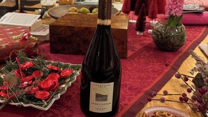 Une pièce chaleureuse avec une cheminée, une bouteille de champagne, des décorations festives et un confortable canapé rouge.