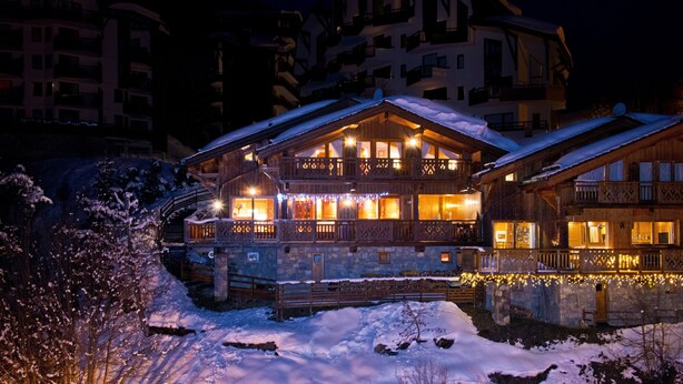Un bâtiment enneigé, doté d’une façade en bois, de balcons et de fondations en pierre.
