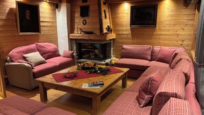Un salon chaleureux avec des murs en bois, une cheminée et des meubles assortis aux couleurs rouge et beige.
