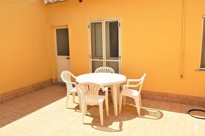 A patio with a white table and chairs, a sliding glass door, and a window. - Holiday Home 'Luca' with Air Conditioning (Porto Cesareo)