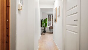A hallway with a wooden door on the left, a potted plant, and a chair in the distance. - City Center, Light & Modern Apartment (Bergen)