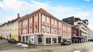 A multi-story building with a red facade and white trim, featuring storefronts on the ground floor. - City Center, Light & Modern Apartment (Bergen)