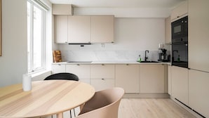 A modern kitchen with white cabinets, a marble countertop, and a black oven. - City Center, Light & Modern Apartment (Bergen)