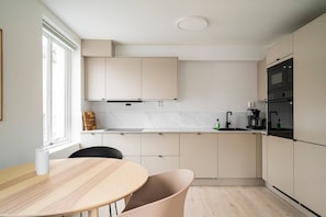 A modern kitchen with white cabinets, a marble countertop, and a black oven. - City Center, Light & Modern Apartment (Bergen)