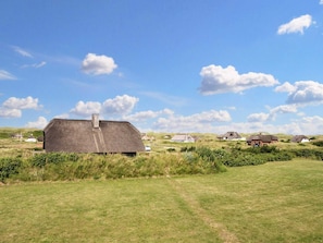 Ländliche Landschaft mit einem großen Gebäude mit Strohdach und mehreren traditionellen Häusern.
