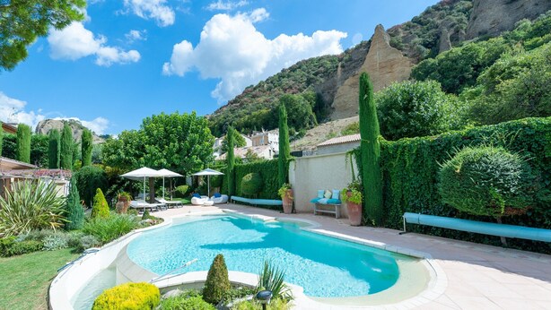 A swimming pool surrounded by greenery, with a mountain in the background.