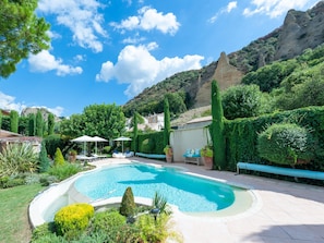 Una piscina rodeada de vegetación, con una montaña al fondo.