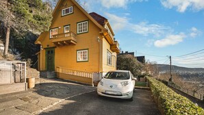 A two-story house with a green door and windows, a car parked in front, and a stone pathway leading to the entrance. - Charming Home with Spectacular Views - NEW! (Bergen)