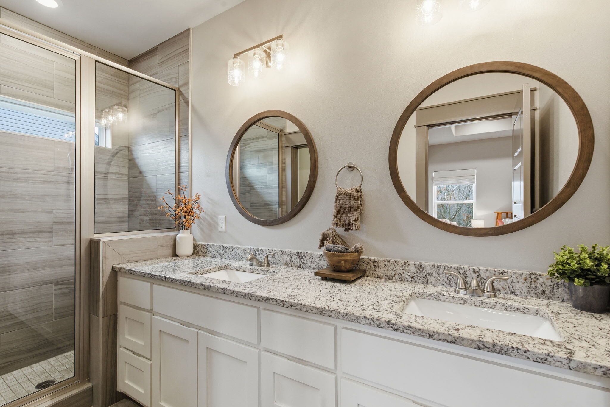 Une salle de bain avec deux lavabos, un grand miroir et une douche.