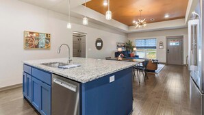 A modern kitchen with a central island, built-in dishwasher, and pendant lighting. - The Allendale Overlook (Bella Vista)