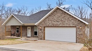 A single-story brick house with a white garage door, a front porch with rocking chairs, and a number 39 on the door. - The Allendale Overlook (Bella Vista)