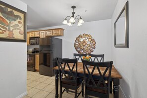A dining area with a wooden table and chairs, a chandelier, and a decorative wall piece. - New Listing! Adventure Ready | Near Arches | Hot Tub + Pool | Views (Moab)