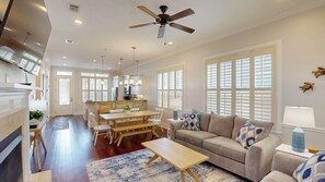 A spacious living area with a dining table, sofa, and a ceiling fan. - Pelican's Nest 3 bedrooms, 3.5 bathrooms (Jekyll Island)