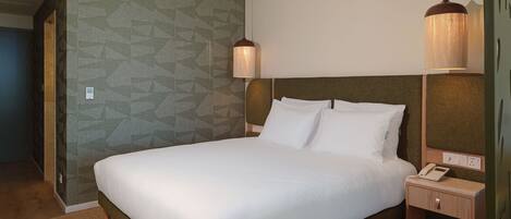 Une chambre d’hôtel avec un lit, une table de chevet, une lampe et un mur décoré d’un motif.