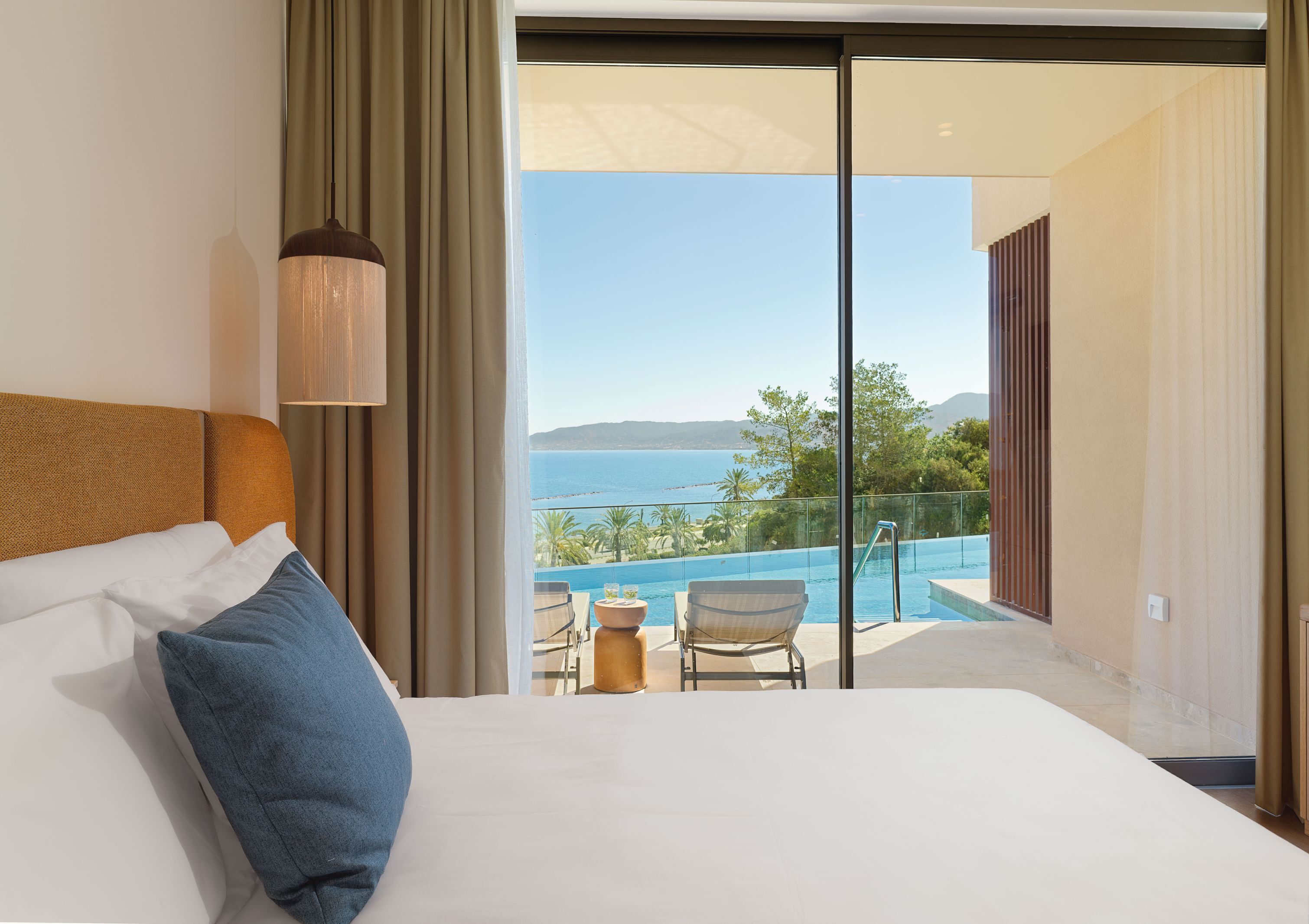 A hotel room with a bed, a view of a swimming pool, and a balcony.