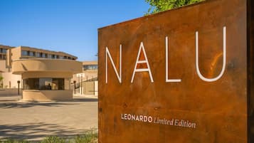 A sign for 'Nalu' with 'Leonardo Limited Edition' text, in front of a modern building with a curved facade.