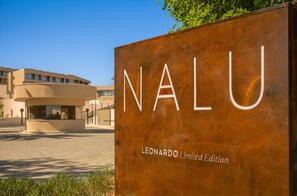 Un cartel que dice 'Nalu' con el texto 'Edición Limitada Leonardo', frente a un edificio moderno de fachada curva.