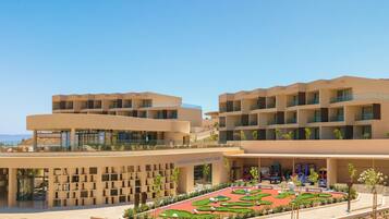Un hotel moderno con varias plantas, asientos exteriores y un jardín ajardinado.