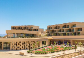 A modern hotel with multiple floors, outdoor seating, and a landscaped garden. - NALU Latchi Leonardo Limited Edition (Polis)