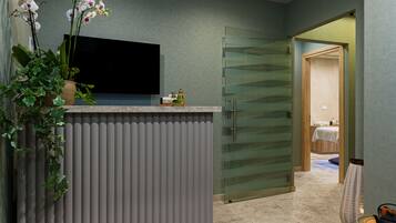 Un baño moderno con mampara de vidrio, lavabo con artículos de aseo y una orquídea en maceta.