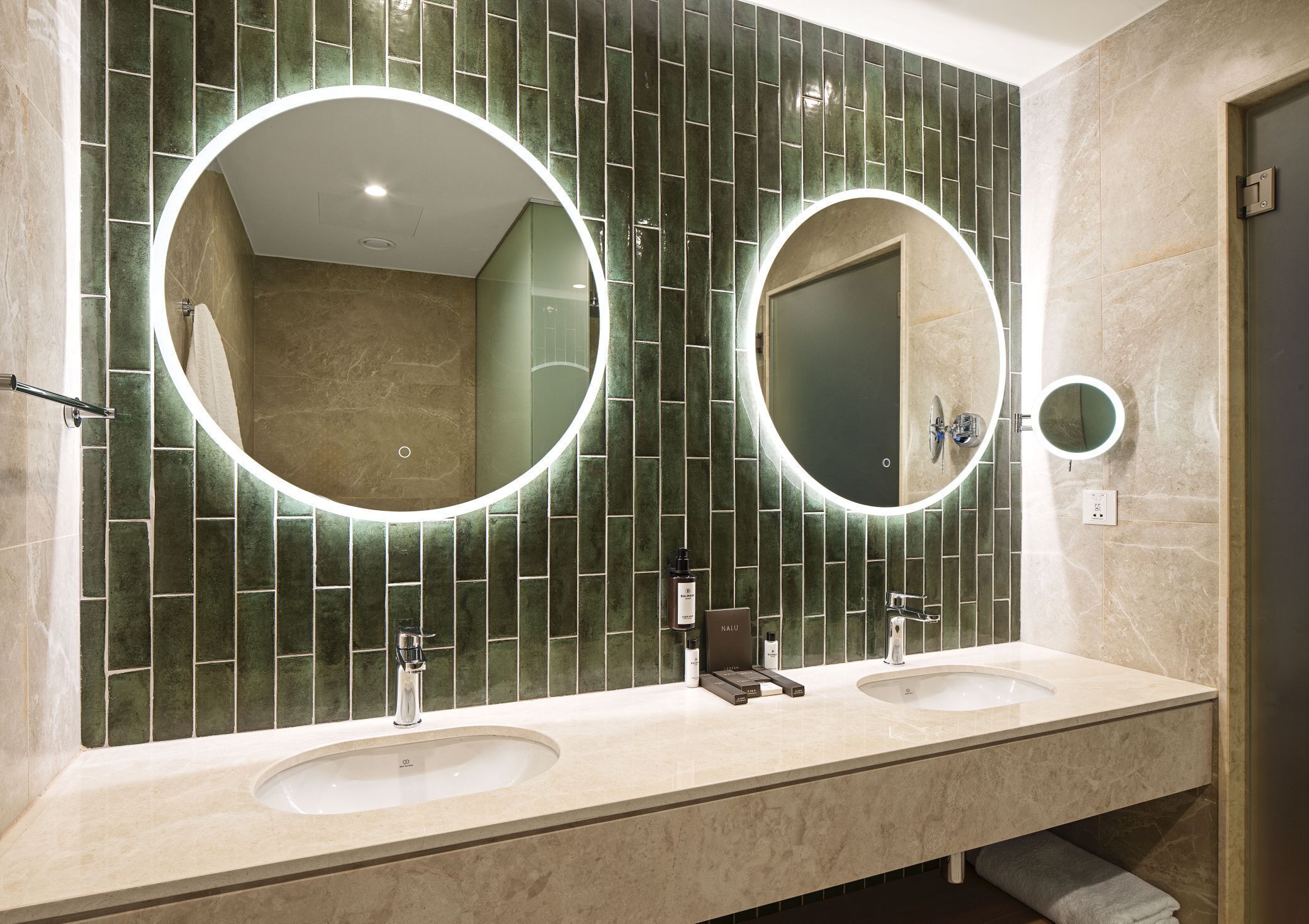 A modern bathroom with two sinks, a large mirror, and a shower area.