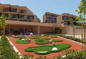 A modern hotel with multiple balconies, a landscaped garden with golf ball-shaped mounds, and a pool area. - NALU Latchi Leonardo Limited Edition (Polis)