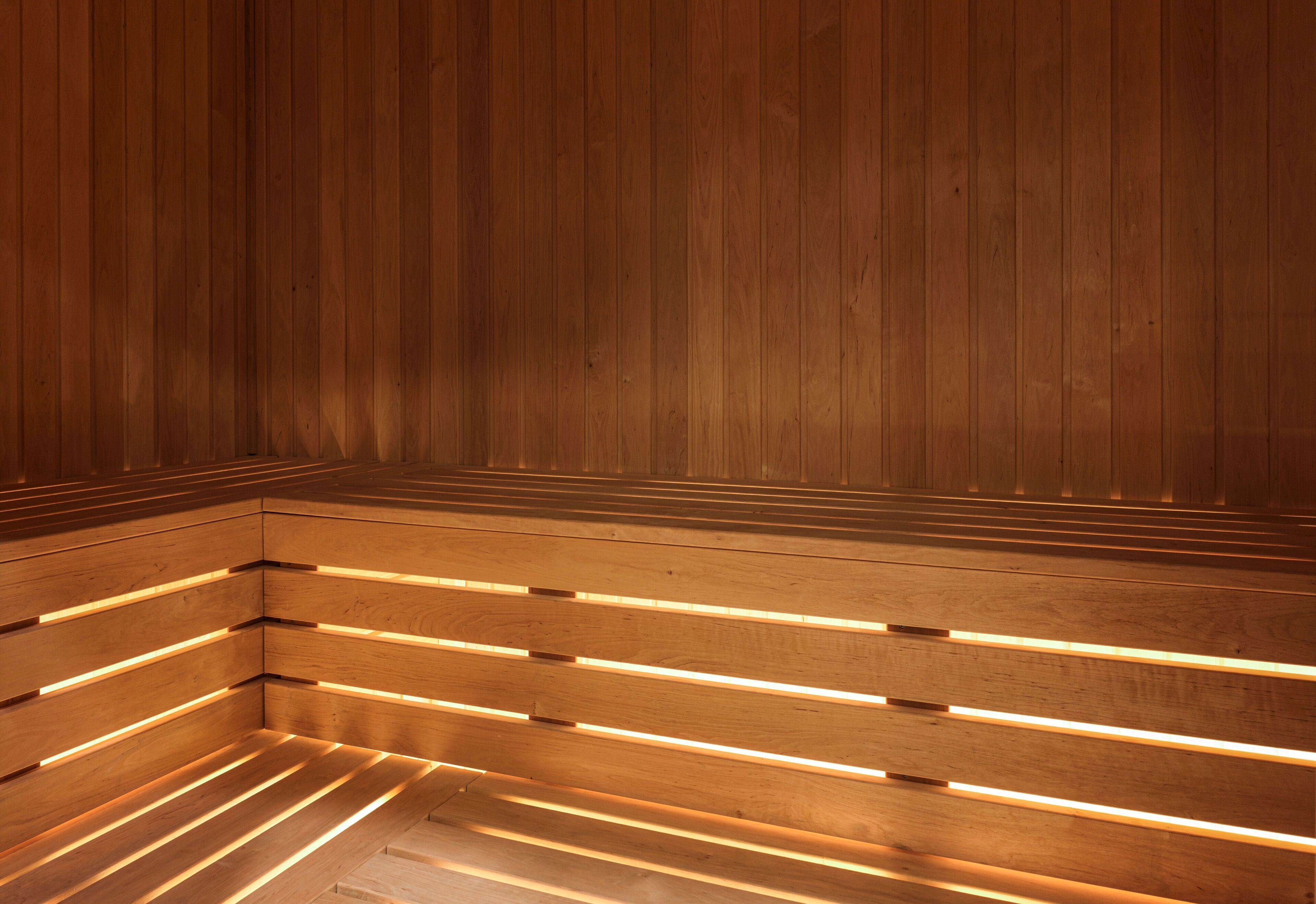 A wooden sauna with slatted benches and warm lighting.