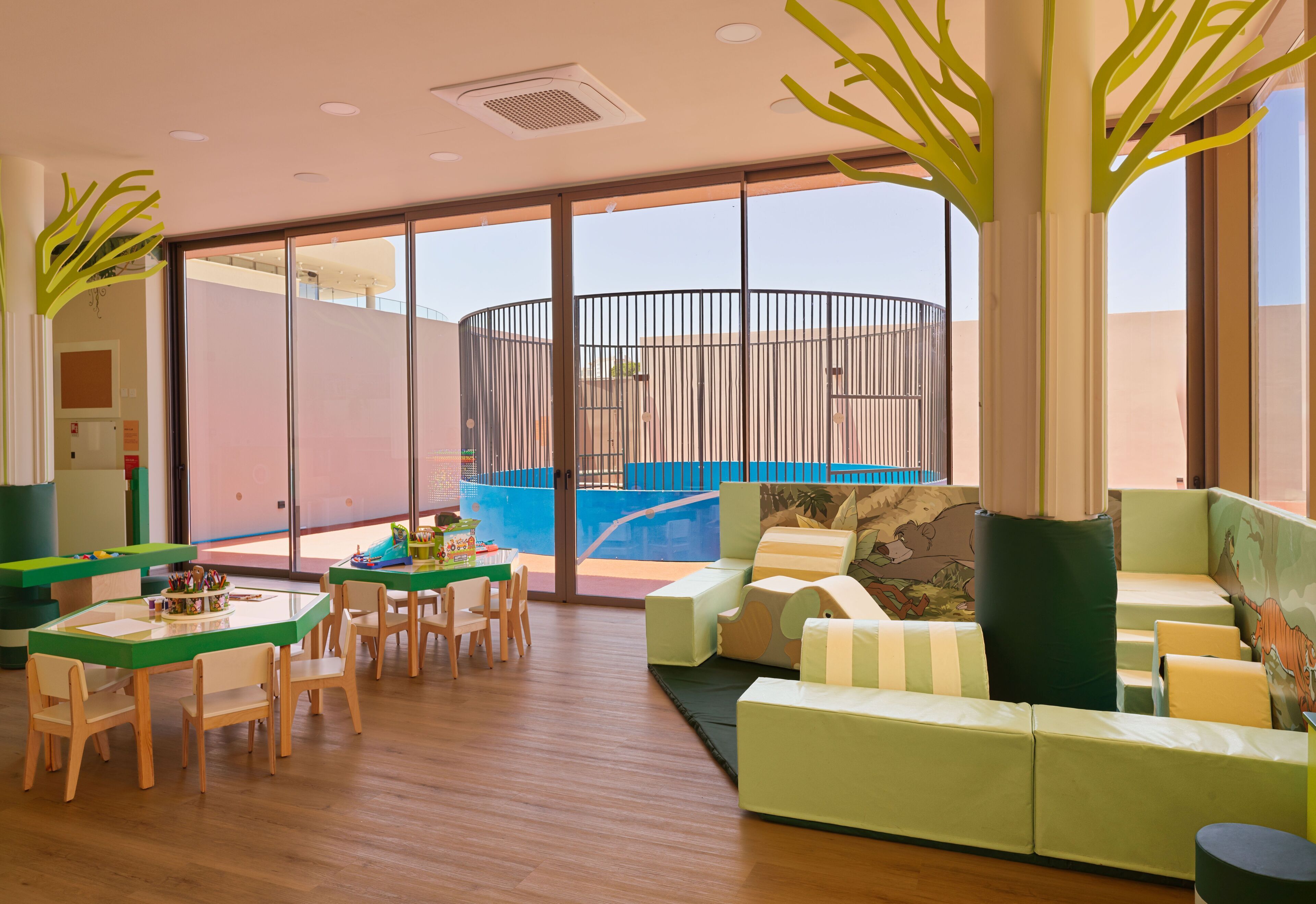 Un interior moderno con piscina, mobiliario verde y un ventanal grande.