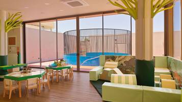 Un interior moderno con piscina, mobiliario verde y un ventanal grande.