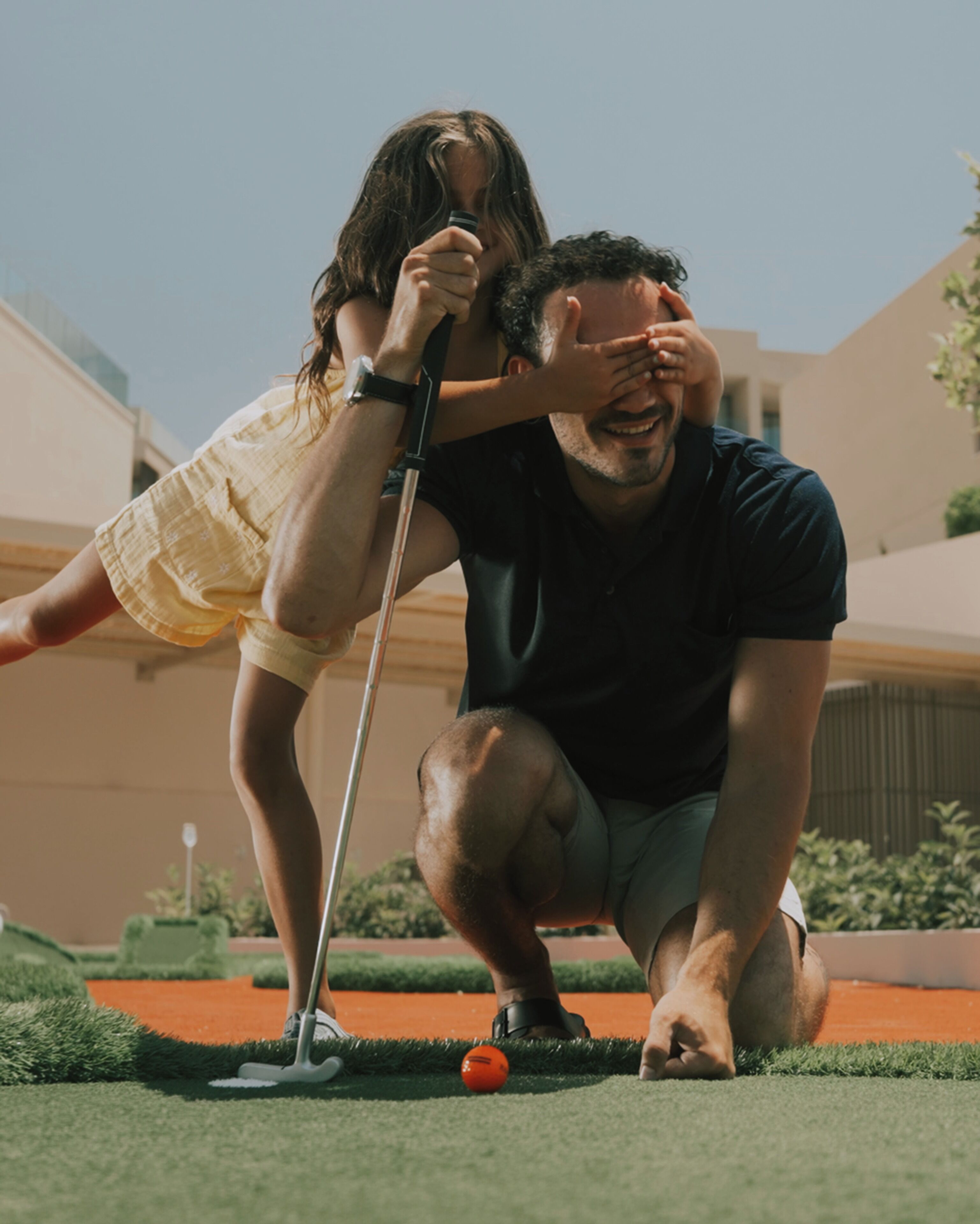 A person playing golf on a green with a golf club and ball.