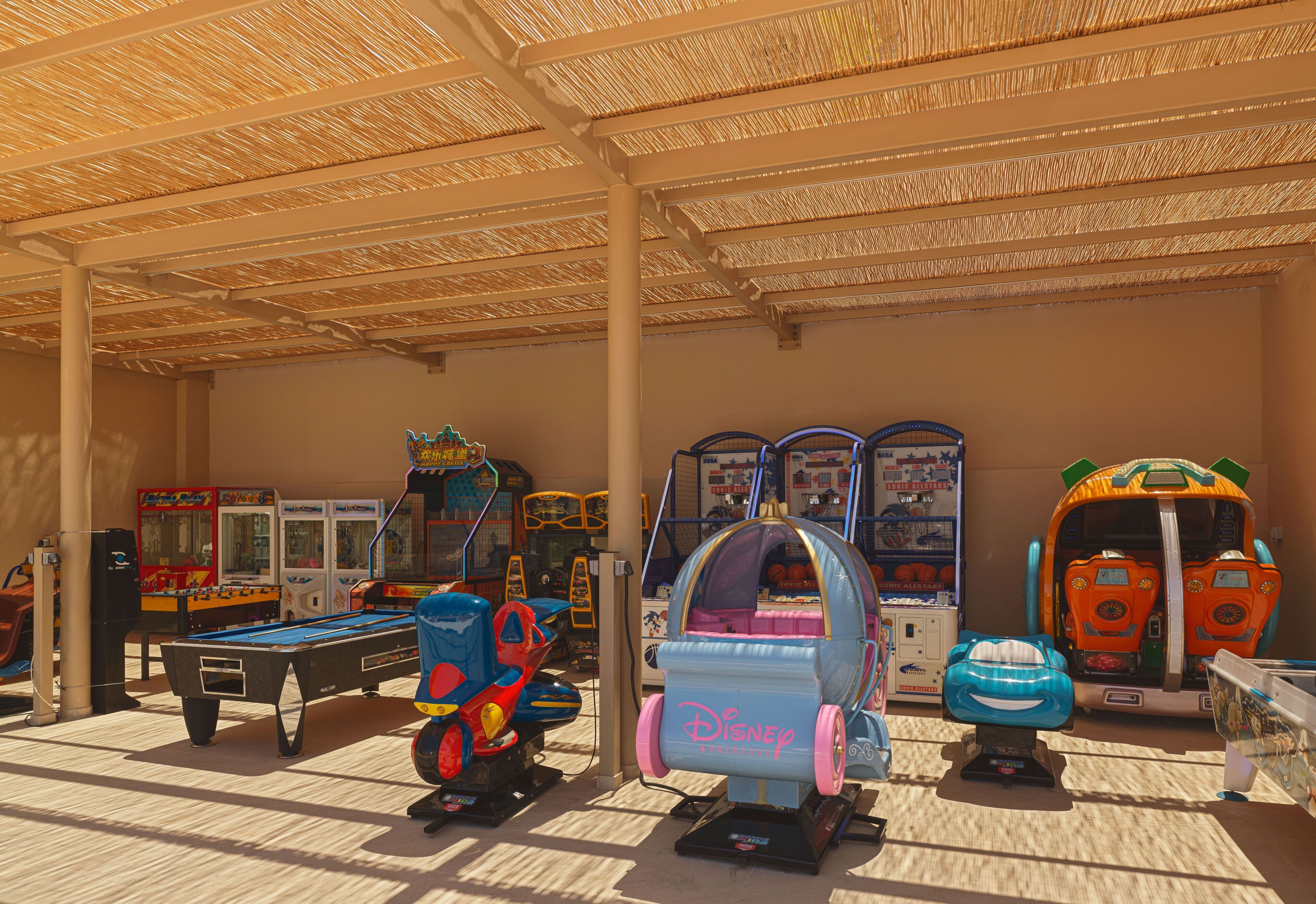 An indoor arcade with various gaming machines, including a ride-on toy and a ball pit.