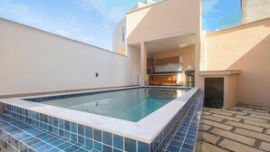 A swimming pool with a tiled edge, a kitchen area, and a patio with stone tiles. - Apt in Condo w/ BBQ Area in Porto - BA MAA (Porto Seguro)