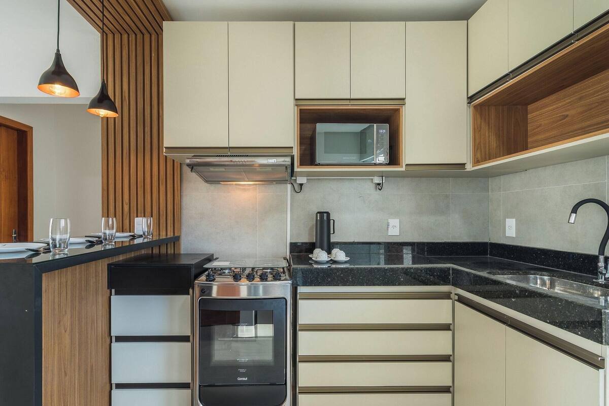 Une cuisine moderne équipée d’une cuisinière à gaz, d’un four, d’un four à micro-ondes et d’un évier avec un robinet.