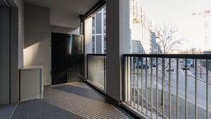 Ein Balkon mit Blick auf eine Stadtstraße, eine schwarze Tür und ein Fliesenboden.