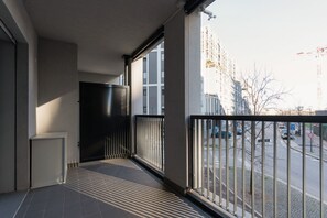 A balcony with a view of a city street, a black door, and a tiled floor. - GuestHost - A comfortable and bright 55 square meters apartment, perfect for four people, located on the first floor of a building with an elevator (NOT accessible to disabled guests).The property is located in the Cascina Merlata neighborhood, a growing (Milan)
