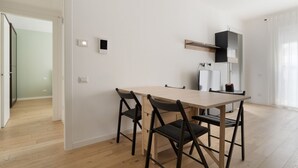 Eine moderne Küche mit Holztisch und -stühlen, einem eingebauten Ofen und einem Kühlschrank.