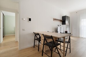 A modern kitchen with a wooden table and chairs, a built-in oven, and a refrigerator. - GuestHost - A comfortable and bright 55 square meters apartment, perfect for four people, located on the first floor of a building with an elevator (NOT accessible to disabled guests).The property is located in the Cascina Merlata neighborhood, a growing (Milan)