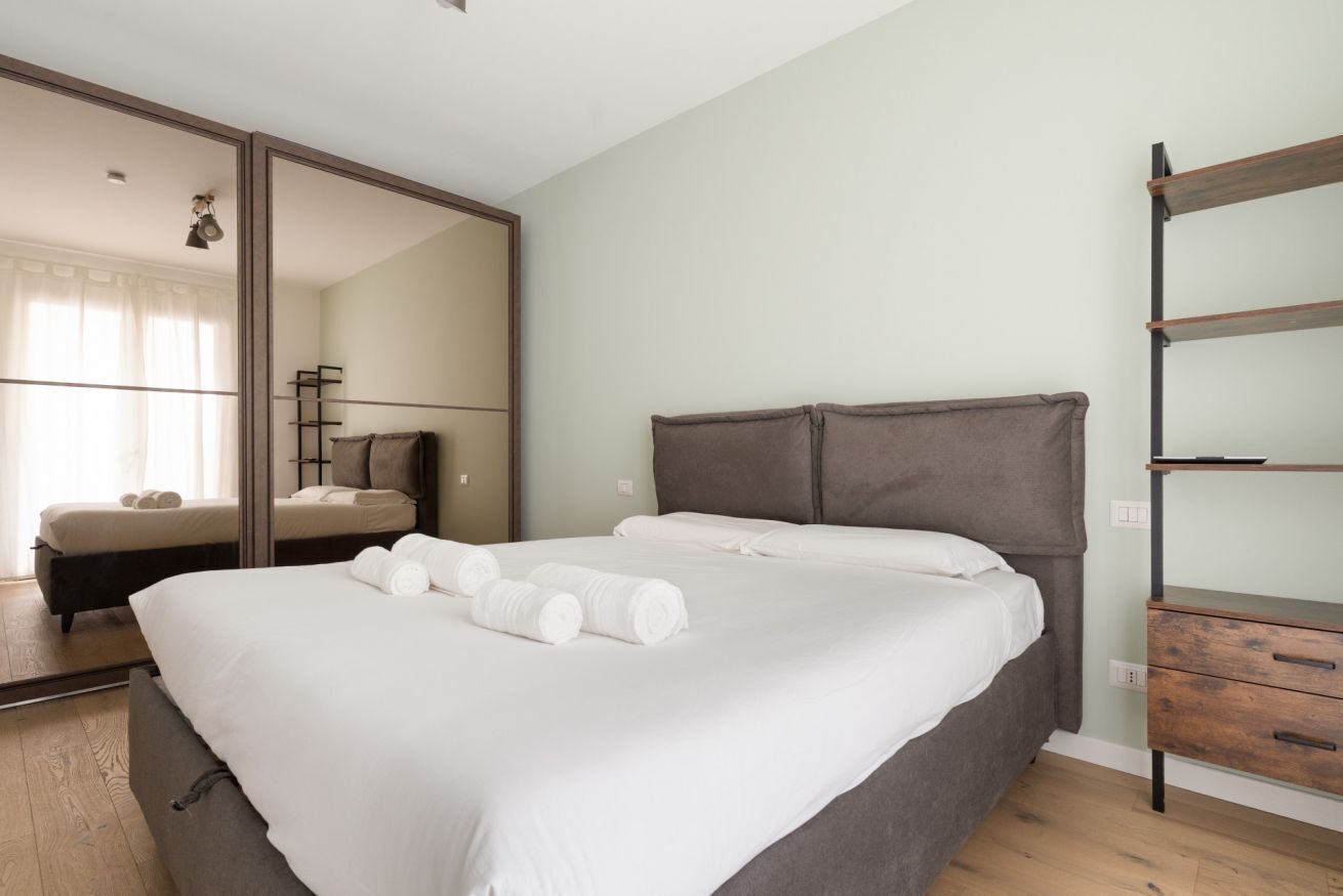 Ein Schlafzimmer mit einem großen Bett, einem Kleiderschrank, einem Spiegel und Holzboden.