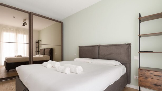 Ein Schlafzimmer mit einem großen Bett, einem Kleiderschrank, einem Spiegel und Holzboden.