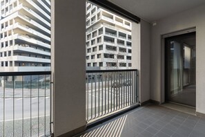 Ein Balkon mit Blick auf ein mehrgeschossiges Gebäude, einer Glastür und einem gefliesten Boden.