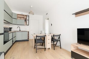 Eine moderne Küche mit Essbereich, integrierten Geräten und einem Fernseher.