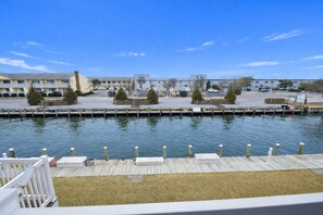 A waterfront view with a dock, a grassy area, and buildings in the background. - Bridgepoint II 201A - Ocean City, MD (Ocean City)