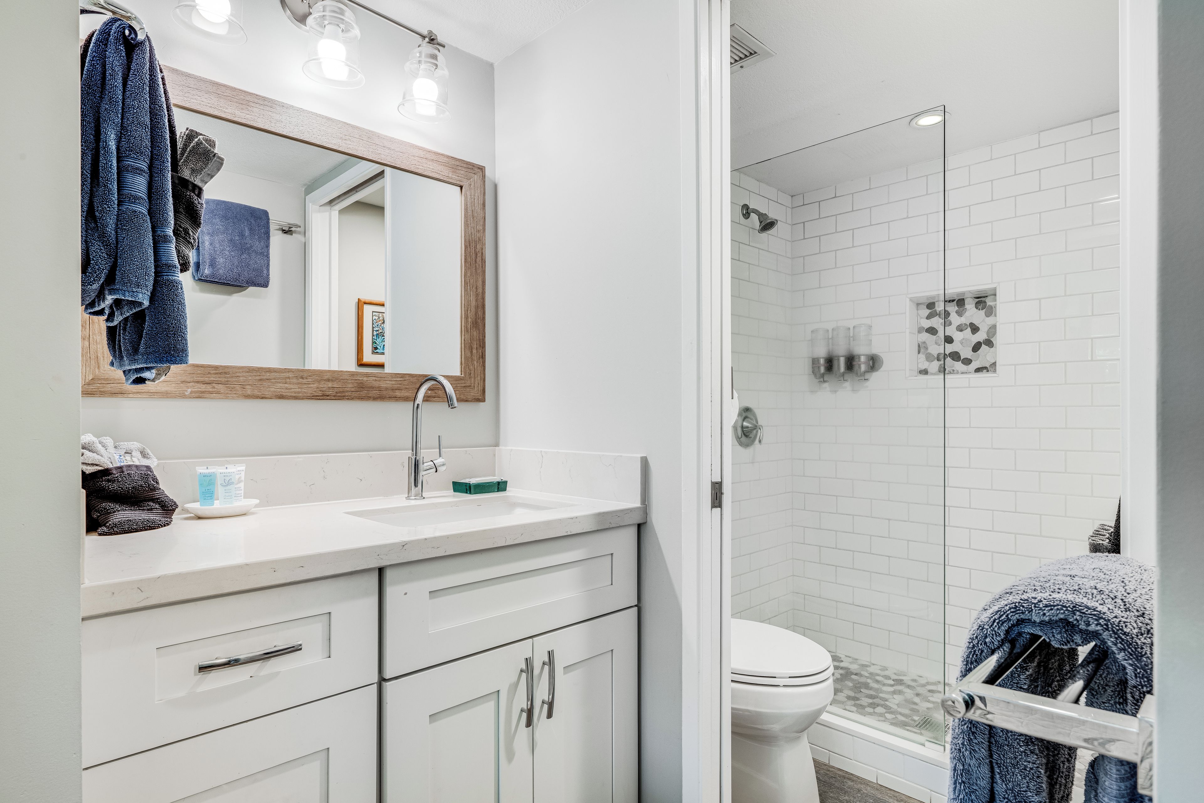 A modern bathroom with a white sink, mirror, and shower area.