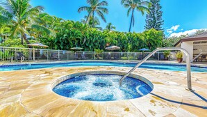 Uma piscina com hidromassagem, rodeada por palmeiras e espreguiçadeiras.