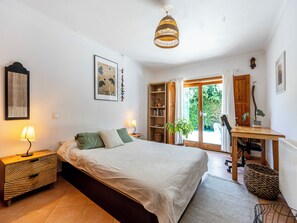 A bedroom with a bed, bedside tables, a desk, and a window with a view of greenery. - Quintinha Mojud - Entire house (Rogil)