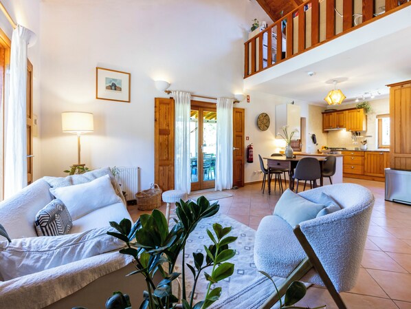 A spacious living area with a sofa set, a dining table, and a kitchen in the background.
