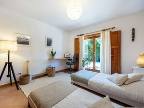 Un dormitorio con dos camas, un escritorio, una silla, una lámpara y una ventana con cortinas.