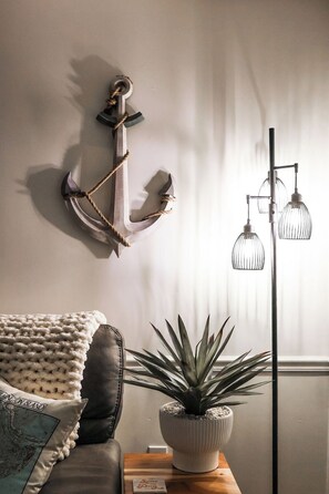 Ein Zimmer mit einer Couch, einem Blumentopf, einer Wanddekoration und einer Stehlampe.