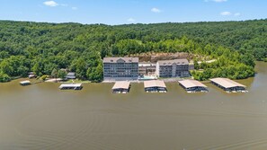 A multi-story hotel with a dock and boat launch area, surrounded by forested hills.