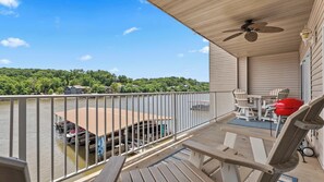 A balcony with a view of a lake, a dock, and a boat.